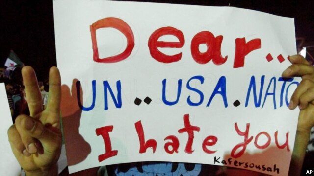 In this citizen journalism image made and provided by the Kfar Suseh Coordinating of the Syrian Revolution on June 18, 2012, anti-Syrian regime protesters hold up a placard during a demonstration at Kfar Suseh area, in Damascus, Syria.