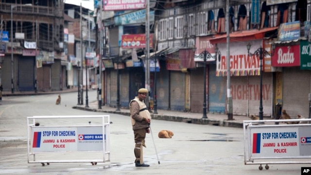 An Indian policeman stands guard at a temporary checkpoint during a curfew in Srinagar, India, March 14, 2013.