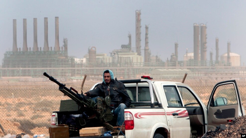 Libya Oil: FILE - In this March 5, 2011 file photo, an anti-government rebel sits with an anti-aircraft weapon in front an oil refinery in Ras Lanouf, eastern Libya. 