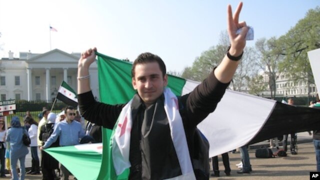 A protest leader unfurls a Syrian flag in front of the White House Saturday, seeking more U.S. action to protect civilians in Syria.