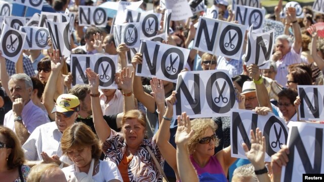 Civil servants hold up placards as they protest against government austerity measures in Madrid, July 23, 2012.