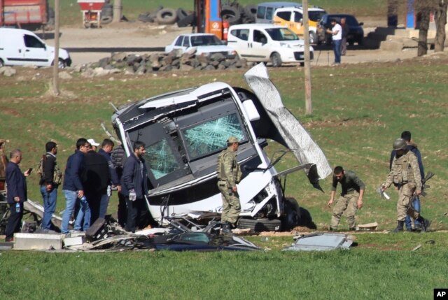 Members of Turkish forces gather around a bus that was destroyed in an explosion on the road linking the cities of Diyarbakir and Bingol, in southeastern Turkey, Feb. 18, 2016. Six soldiers were killed after PKK rebels detonated a bomb on the road.