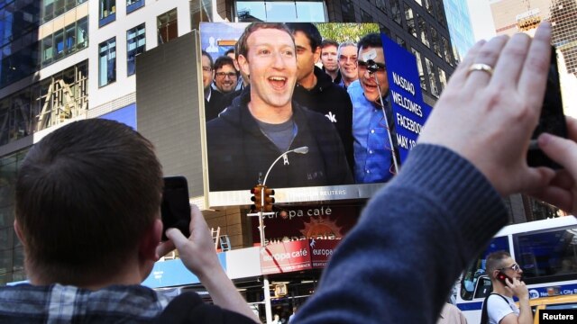 El fundador de Facebook, Mark Zuckerberg, aparece en las pantallas de Menlo Park, tras la salida a la venta de las acciones de la empresa de internet.