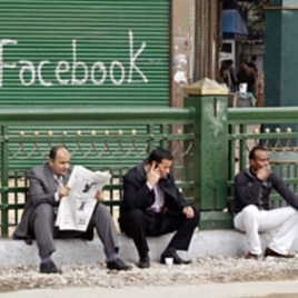 Anti-government protesters sit next to a "Facebook" graffiti sign during demonstrations inside Tahrir Square in Cairo (File)