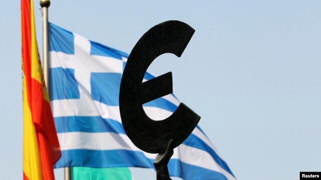 FILE - A Greek flag flies behind a statue to European unity outside the European Parliament in Brussels.