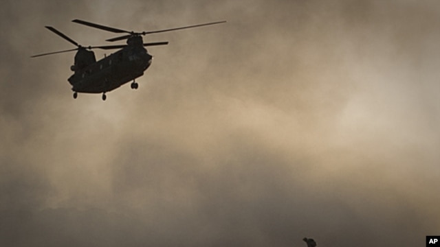 A US Marine tries to shelter from the dust as a Chinook helicopter arrives to pick up supplies at Forward Operating Base Edi in the Helmand Province of southern Afghanistan,June 9, 2011 file photo