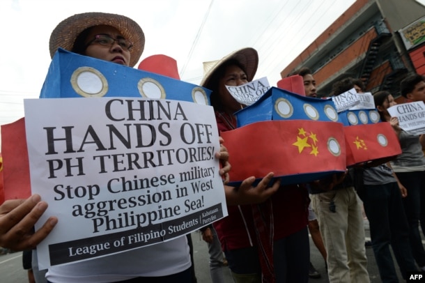 FILE - Filipino student activists hold mock Chinese ships to protest recent island-building and alleged militarization by China off the disputed Spratlys group of islands in the South China Sea, during a rally in Manila, Philippines, March 3, 2016.