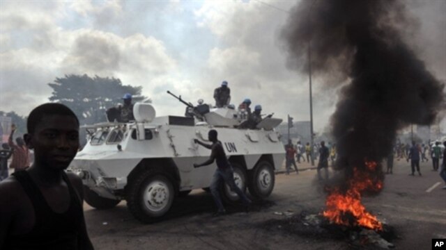 UN peacekeepers drive past supporters of Alassane Ouattara as they demonstrate and burn tires in the Abobo neighbourhood in Abidjan, February 19, 2011