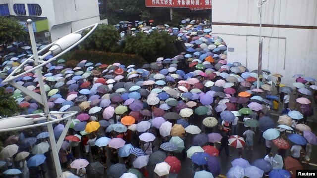Local residents gather in front of a municipal government building in Shifang county, Sichuan province, in this handout picture taken July 2, 2012. 