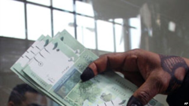 A woman displays Sudan's new currency at the central bank in Khartoum, Sudan. The Sudanese government began circulating a new edition of the Sudanese pound on Sunday as a precautionary measure following the loss of oil revenues resulting from South Sudan'