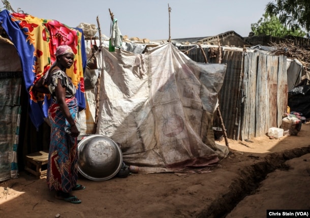 FILE - A woman stands outside a makeshift house at an internally displaced persons camp in Maiduguri, Nigeria, March 24, 2016.