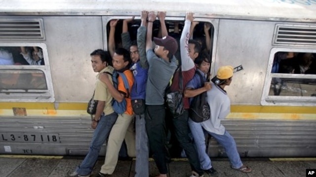 Indonesian men struggle to board a packed commuter train at a station in Jakarta, May 11, 2010.
