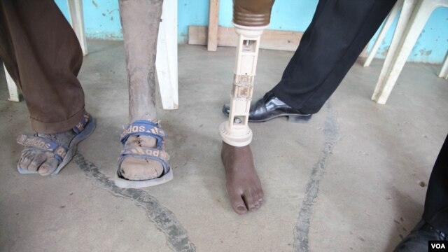 A patient at the International Committee of the Red Cross amputee center took the prosthetic leg of a deceased relative after years of waiting, Rumbek, South Sudan, February 2013. (H. McNeish/VOA)
