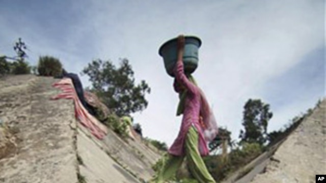 An Indian girl crosses over a stream of polluted water as she carries drinking water on the outskirts of Jammu, India, March 21, 2011