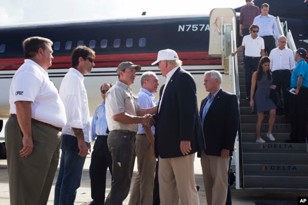 Republican presidential candidate Donald Trump, followed by his running mate, Indiana Gov. Mike Pence, shakes hands with Louisiana Attorney General Jeff Landry as he is greeted by Louisiana officials upon his arrival at the Baton Rouge airport.