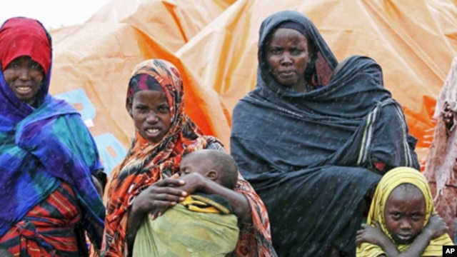 An internally displaced Somali family stand in the rain outside their makeshift shelter in the south of Mogadishu's Hodan district, August 2, 2011