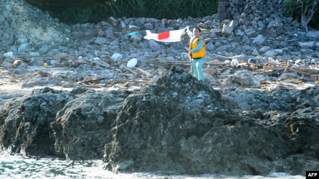 A Japanese activist waves the country's flag after landing on a group of islands known as Senkaku in Japanese and Diaoyu in Chinese, August 19, 2012.