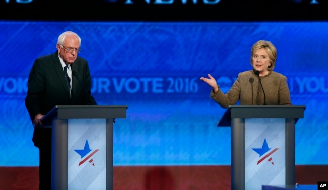 Bernie Sanders, left, listens as Hillary Clinton speaks during a Democratic presidential primary debate at Saint Anselm College in Manchester, N.H., Dec. 19, 2015.
