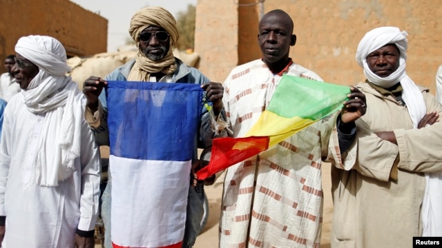 People hold Malian and French flags during the reopening ceremony of Mahamane Fondogoumo elementary school in the town center of Timbuktu February 1, 2013. REUTERS/Benoit Tessier (MALI - Tags: POLITICS SOCIETY EDUCATION) - RTR3D7ZT