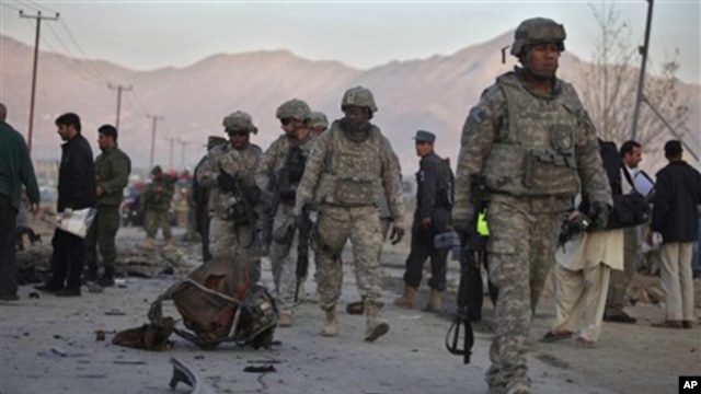 U.S. soldiers walk past the scattered parts of a vehicle used in an explosion on the outskirts of Kabul, Afghanistan, 12 Nov. 2010.