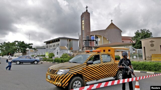 A police officer stands guard outside the Holy Trinity Catholic Church in Nigeria's capital Abuja, June 24, 2012, after tit-for-tat attacks between Muslims and Christians in Kaduna, sparked by suicide bombings blamed on Islamist sect Boko Haram.