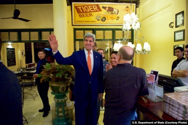 U.S. Secretary of State John Kerry waves to tourists after he entered the famed Foreign Correspondents Club in Phnom Pehn, Cambodia, Jan. 25, 2016.