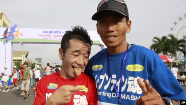 Japanese entertainer Neko Hiroshi, left, poses with Cambodian winner Em Buntin after a half marathon Saturday, June 18, 2011 in Phnom Penh, Cambodia. The Japanese finished second. More than 1,000 Cambodians and foreigners took part in the running, celebra