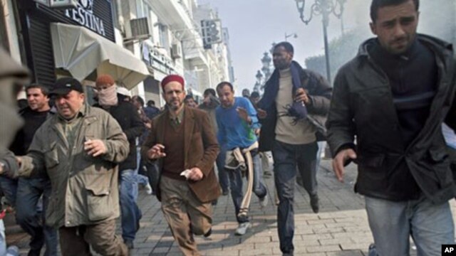 Protestors run away from tear gas during a demonstration against former Tunisian President Zine El Abidine Ben Ali in the center of Tunis, 17 Jan 2011