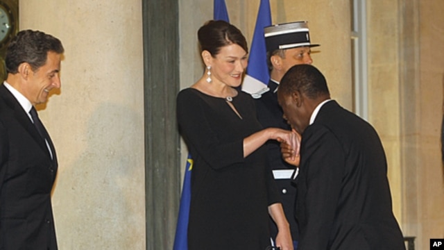 France's President Nicolas Sarkozy, left, and Carla Bruni-Sarkozy welcome Ivory Coast President Alassane Ouattara as he arrives for a state dinner at the Elysee Palace in Paris, January 26, 2012.