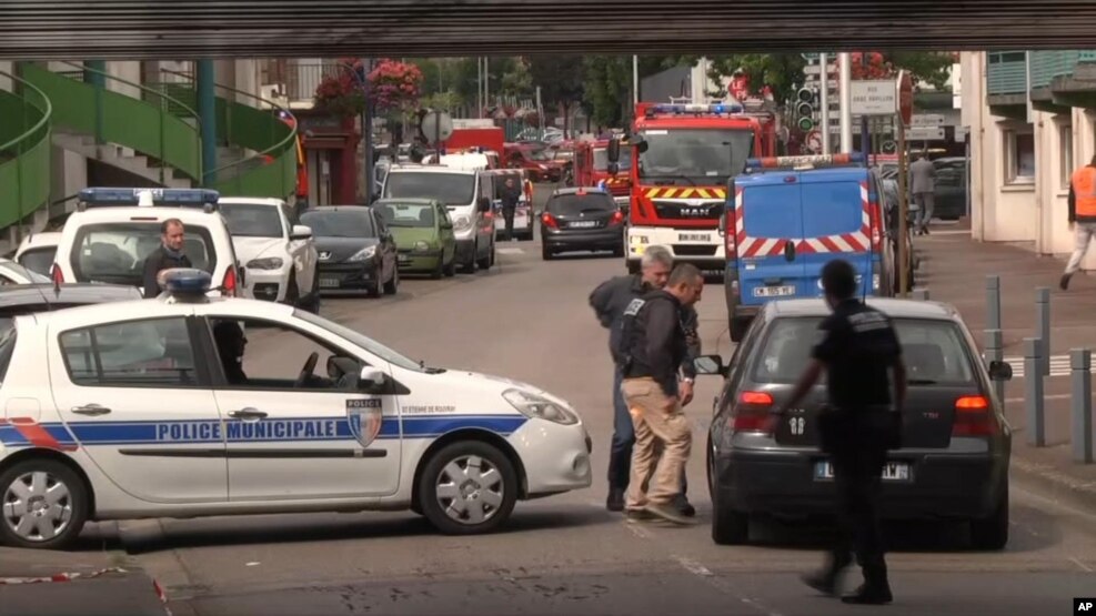 Oficiales de policía hablan con un conductor mientras cierran calles en torno a una situación de toma de rehenes en Normandía, Francia, el martes, 26 de julio de 2016.
