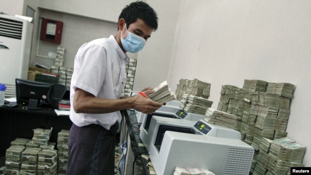 An employee counts Burmese kyat banknotes in a bank in the capital, Rangoon, April 5, 2012.
