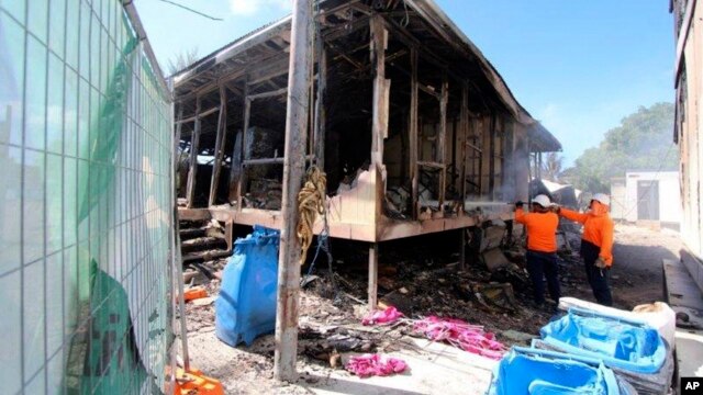 This photo supplied by Australian Department of Immigration and Citizenship shows workers extinguishing the last smouldering embers after some125 asylum seekers rioted in Nauru, Friday July 19, 2013. 