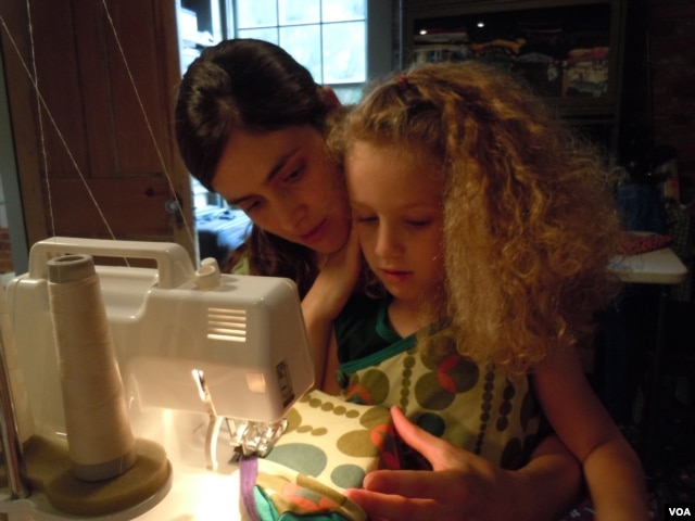 Shannon Kline, shown with daughter Alice, uses organic cotton and recycled fabric in a kids clothing business she runs out of her home. (VOA/J. Taboh)