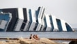 June 20, 2012: Vacationers bask in front of the wreckage of capsized cruise liner Costa Concordia near the harbour of Giglio Porto.