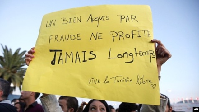 A Tunisian demonstrator holds a sign that says "things acquired fraudulently never last long" during a protest against the Islamist Ennahda movement in Tunis, October 26, 2011.