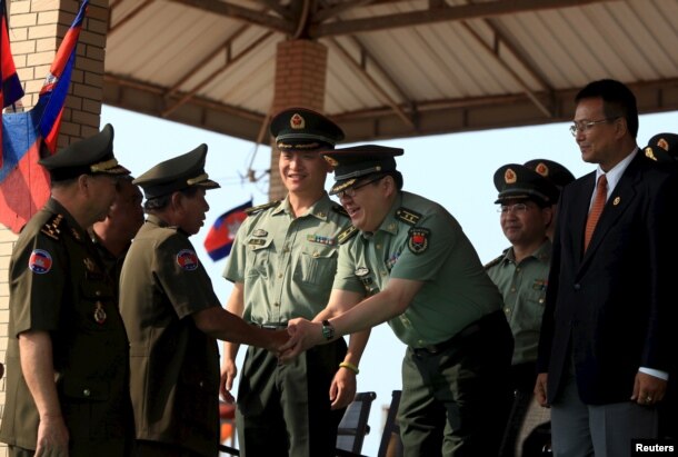 FILE - Cambodian Defense Minister Tea Banh, second left, shakes hands with a Chinese army adviser during a graduation ceremony at the Army Institute in Kampong Speu province. Cambodia has backed Chinese maritime claims across islands and waters in the South China Sea.