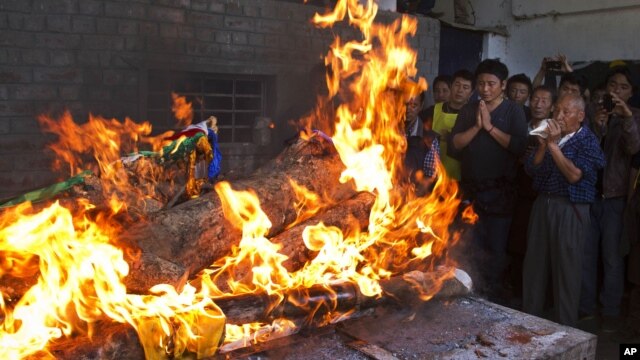Tibetan exiles pray next to the burning funeral pyre of 27-year-old Jamphel Yeshi, who died two days after he immolated himself in Dharmsala, India, March 30, 2012. 