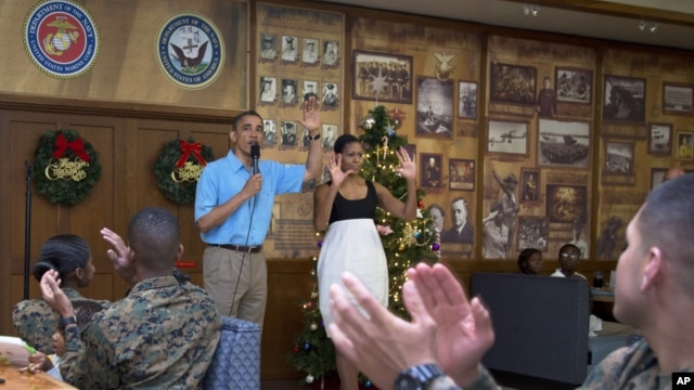 Presiden Amerika Barack Obama dan ibu negara Michelle Obama disambut meriah oleh para anggota dan keluarga militer AS di Anderson Hall, Pangkalan Angkatan Laut di Kaneohe, Hawaii , 25 Desember 2012. (AP Photo/Carolyn Kaster). Presiden Obama akan mempersingkat liburannya dan diperkirakan akan tiba kembali di Washington, Kamis pagi (27/12).