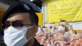 A policeman stands in front of pile of seized drugs during narcotics destruction ceremony in Thailand, 2004. 