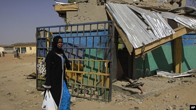An unidentified woman walks past the ruins of a market outside the state police headquarters in Kano, Nigeria. Police said that members of the radical Islamist group Boko Haram dressed in uniforms resembling those of soldiers and police officers when they