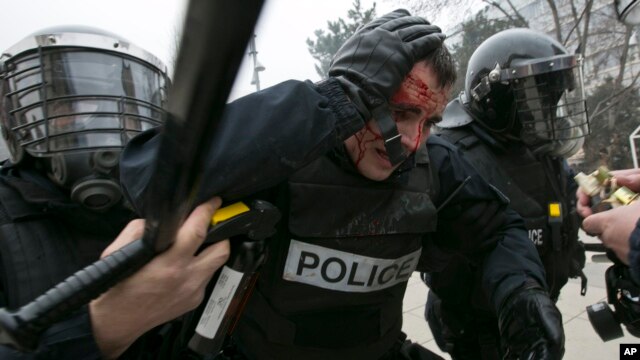 An injured policeman is helped by colleagues during a protest in Kosovo's capital Pristina, Jan. 27, 2015