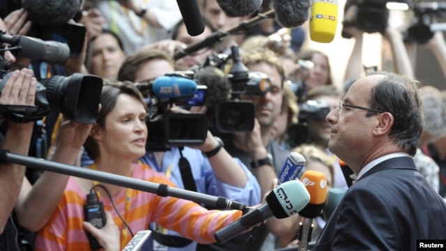France's President Francois Hollande (R) talks to the media as he arrives at an informal EU leaders summit in Brussels, May 23, 2012.