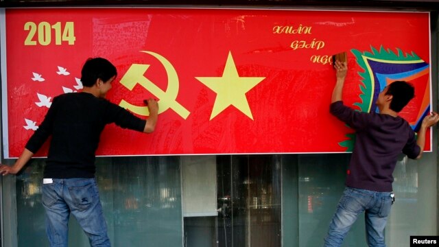 Công nhân đánh bóng poster mừng Tết Nguyên đán trên đường phố ở Hà Nội, ngày 23/1/2014.