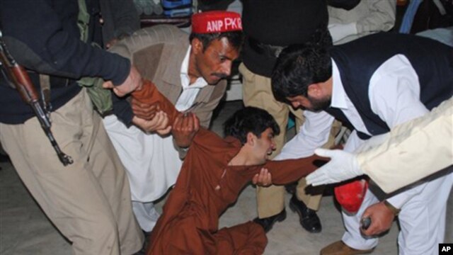 People try to comfort a boy who lost his family member, at a local hospital in Peshawar, Pakistan, Monday, Feb 27, 2012.