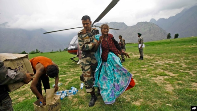 Indian army soldier helps an injured Indian pilgrim after she was rescued from the higher reaches of mountains, at a makeshift helipad at Joshimath, in northern Indian state of Uttarakhand, June 24, 2013.