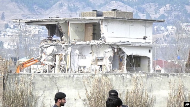 Policemen and residents stand near while demolition work is carried out on the building where al Qaeda leader Osama bin Laden was killed by U.S. special forces last May, in Abbottabad, February 26, 2012.