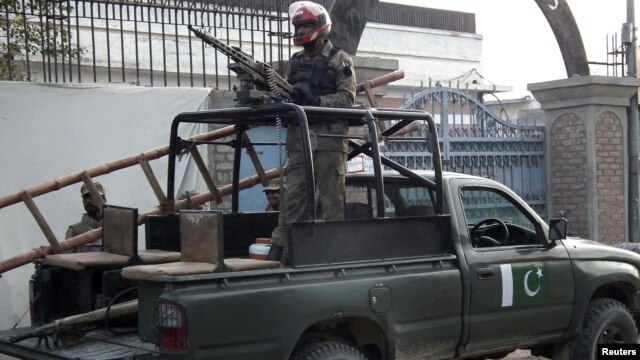 Pakistani security forces stand guard at the site of a deadly blast by four Taliban suicide bombers in Bannu, Pakistan, December 10, 2012.