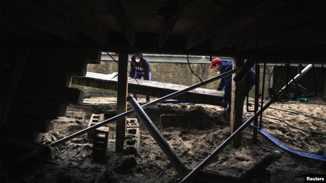 Rose (L) and Dan Driscoll help move debris away from their parents' basement that had been flooded two months ago by Superstorm Sandy in the Queens borough region of Breezy Point, New York, December 29, 2012. 