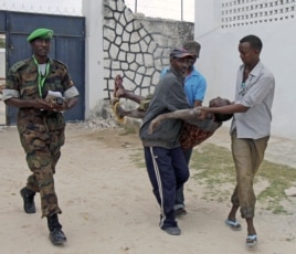 Somali police men in Mogadishu carry a soldier who was injured as two suicide bombers tried to blow up the constituent assembly venue before being shot dead by security forces, Aug.1, 2012.