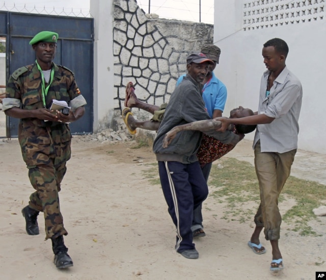 Somali police men in Mogadishu carry a soldier who was injured as two suicide bombers tried to blow up the constituent assembly venue before being shot dead by security forces, Aug.1, 2012.